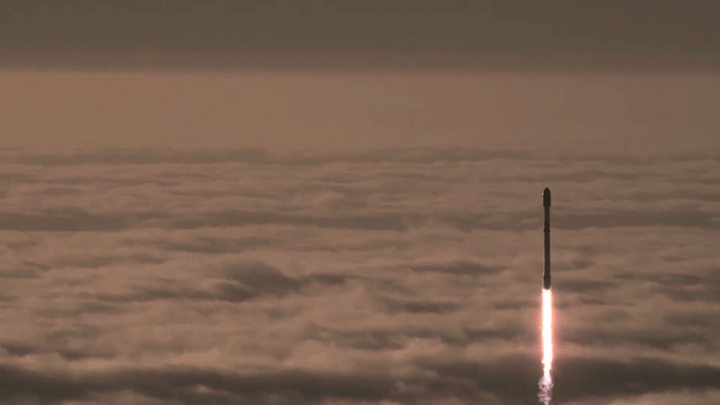 Animated view of a Falcon 9 rocket rising above a cloud deck.